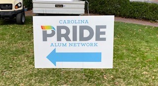 Sign for the Carolina Pride Alum Network at the 3rd Annual Homecoming Weekend, at a tailgate by the Bell Tower